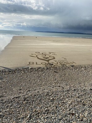 Ein Strand mit einem herzförmigen Muster im Sand und den Worten 'LOVE PLANTS' darin geschrieben.