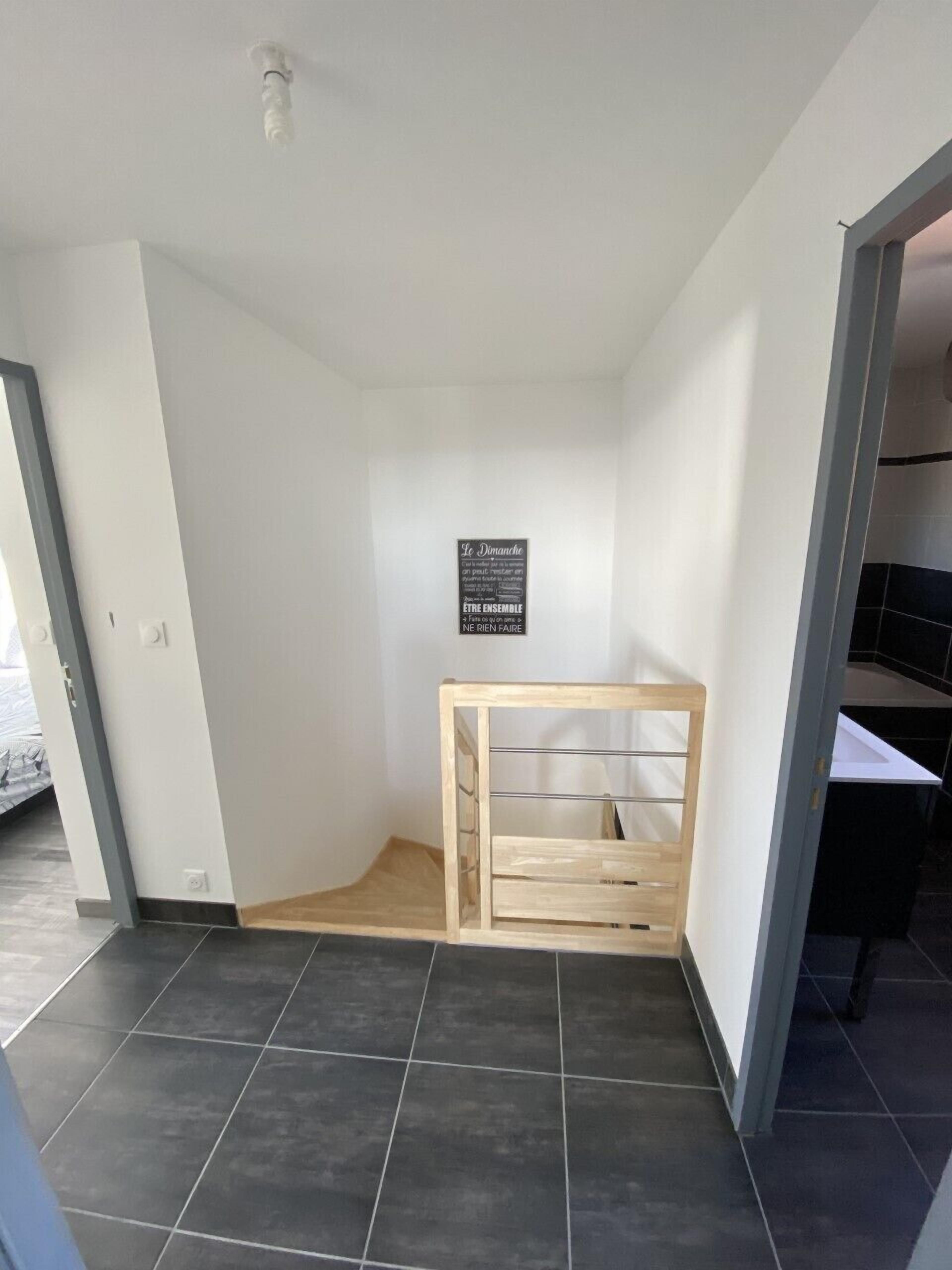 A room with a wooden bench, a black sign with white text, and a tiled floor.