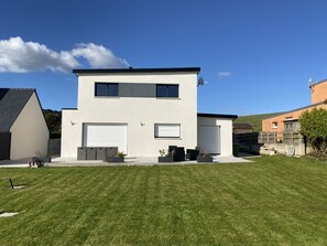 Una casa moderna de dos pisos con garaje, césped cuidado y antena parabólica.