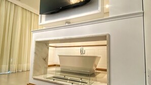 A modern living room with a flat-screen TV mounted above a built-in fireplace. - Pousada Ville Vie (Gramado)