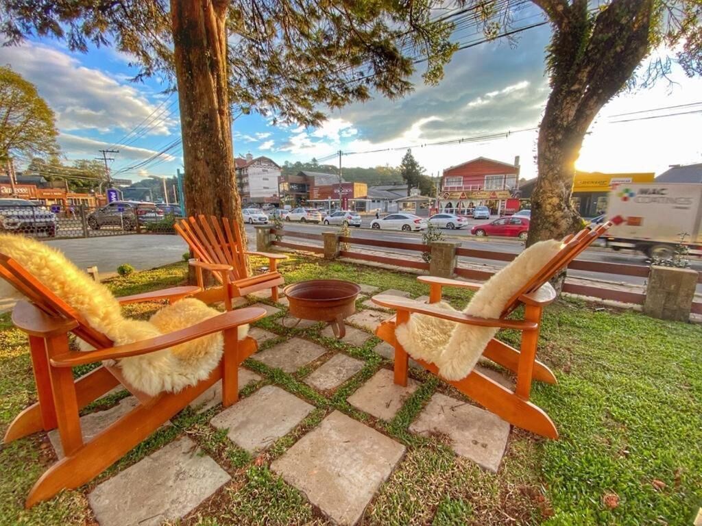A patio with wooden chairs and a fire pit, overlooking a busy street with cars and buildings.