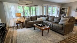 A living room with a sectional sofa, a coffee table, and a bookshelf. - Secluded 4BR Cottage Near Lake Michigan—Decks, Fire Pit & Pet‑Friendly (South Haven)