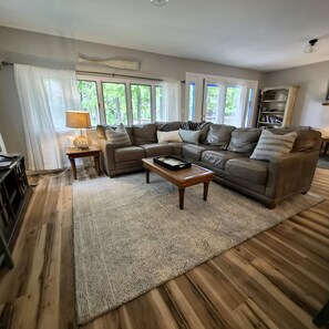 A living room with a sectional sofa, a coffee table, and a bookshelf. - Secluded 4BR Cottage Near Lake Michigan—Decks, Fire Pit & Pet‑Friendly (South Haven)