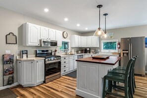 A modern kitchen with white cabinetry, stainless steel appliances, and a wooden island. - Secluded 4BR Cottage Near Lake Michigan—Decks, Fire Pit & Pet‑Friendly (South Haven)