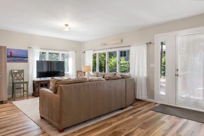 A living room with a large sofa, a television, and a window with curtains.