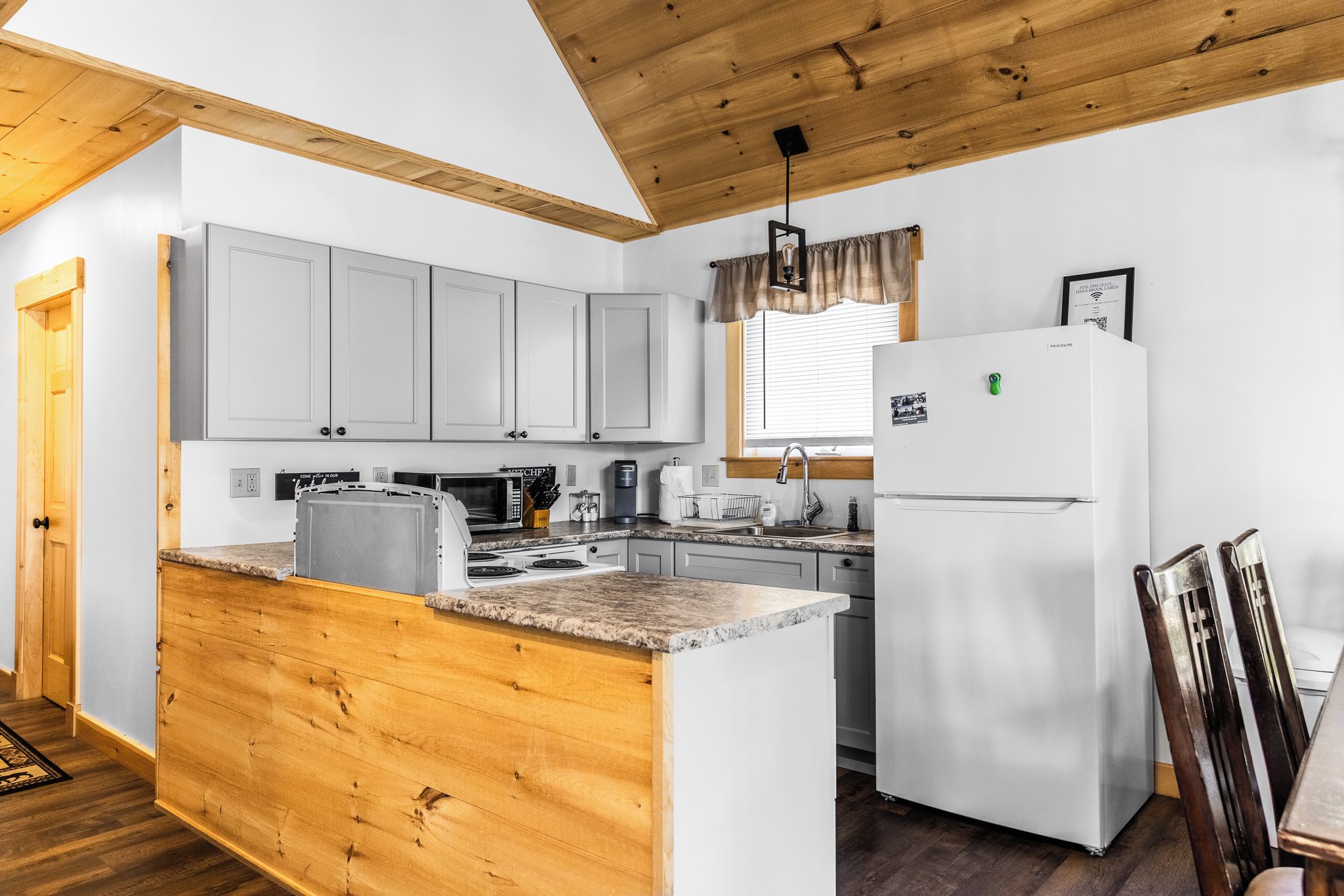 A kitchen with wooden cabinets, a white refrigerator, and a granite countertop.