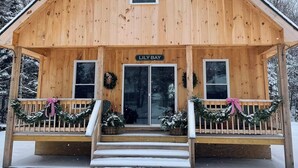 Una baita in legno con veranda, chiamata "Lily Bay", con una porta d'ingresso, due finestre e un cartello sopra la porta.