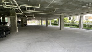 An empty parking garage with concrete pillars and overhead pipes. - Luxury Beach Condo (Madeira Beach)