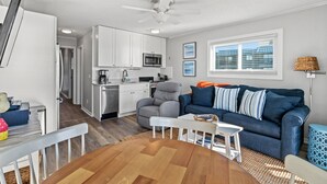 A modern kitchen with white cabinets, a gray chair, and a blue couch.