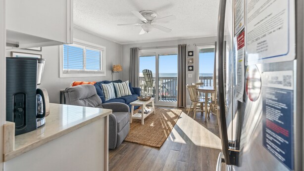 A modern living room with a sofa, coffee table, and a view of the ocean through large windows.