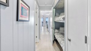 A narrow hallway with a bed on the right and a framed picture on the left.