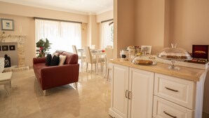 Una sala de estar moderna con un sofá rojo, un comedor con sillas blancas y una cocina con armarios blancos y una encimera de madera.