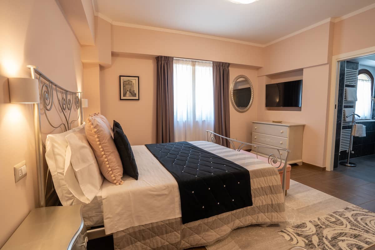 Une chambre à coucher comprenant un lit, une table de chevet, une commode et un miroir.