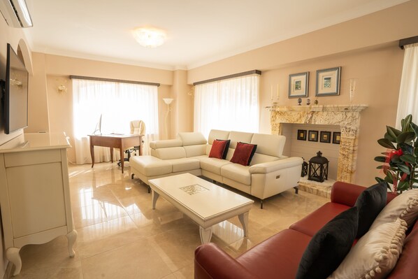 A living room with a sectional sofa, a coffee table, a TV, and a fireplace. - Il Castellaccio (Spello)