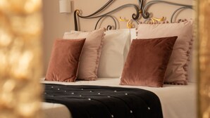 Una cama bien hecha con colcha a rayas blancas y negras, cabecera metálica y varias almohadas.