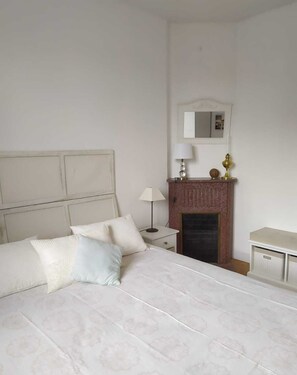 Cozy retreat with a large bed, nightstand, and fireplace.