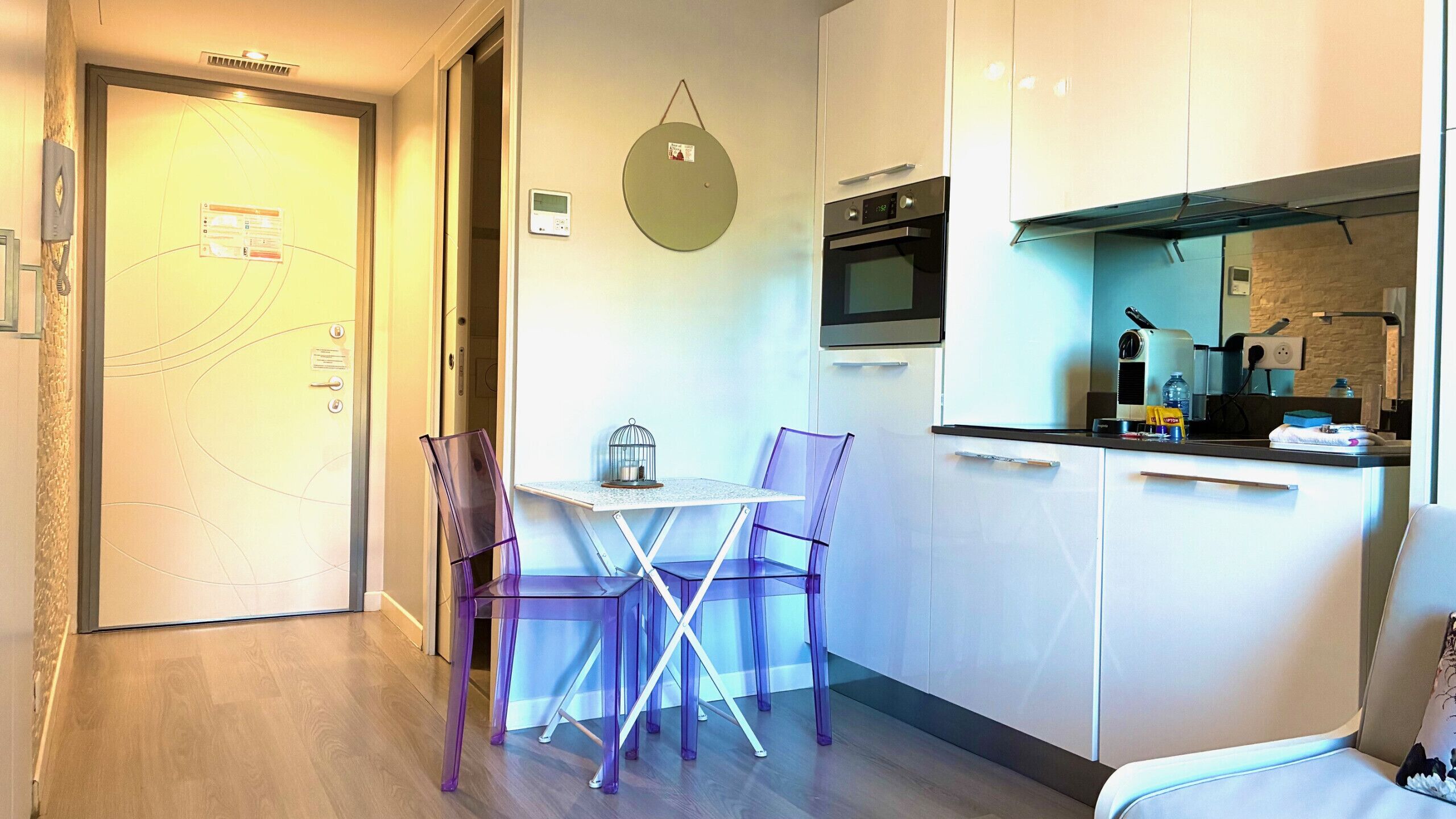Une cuisine compacte dotée d’appareils électroménagers modernes, une table à manger avec des chaises et un petit coin salon.