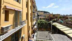 A narrow urban street with yellow buildings, balconies, and a clear sky. - Maison Linda (Niza)
