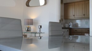 Une cuisine moderne avec des meubles en bois, une table à manger en verre et un miroir.