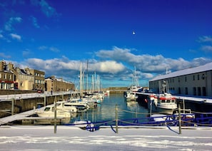 A marina with boats docked, a building with a sign, and a clear sky.