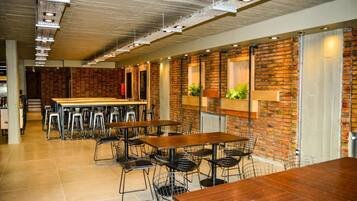 Un restaurante moderno con paredes de ladrillo, mesas de madera y sillas de metal.