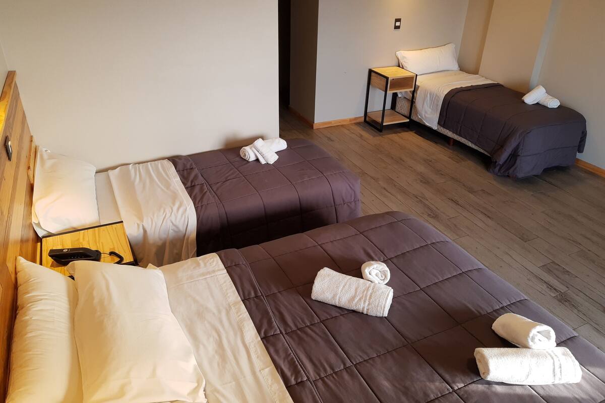 Ein Hotelzimmer mit zwei Betten, jeweils mit einem Holzkopfstück, einem Nachttisch und einer Lampe.