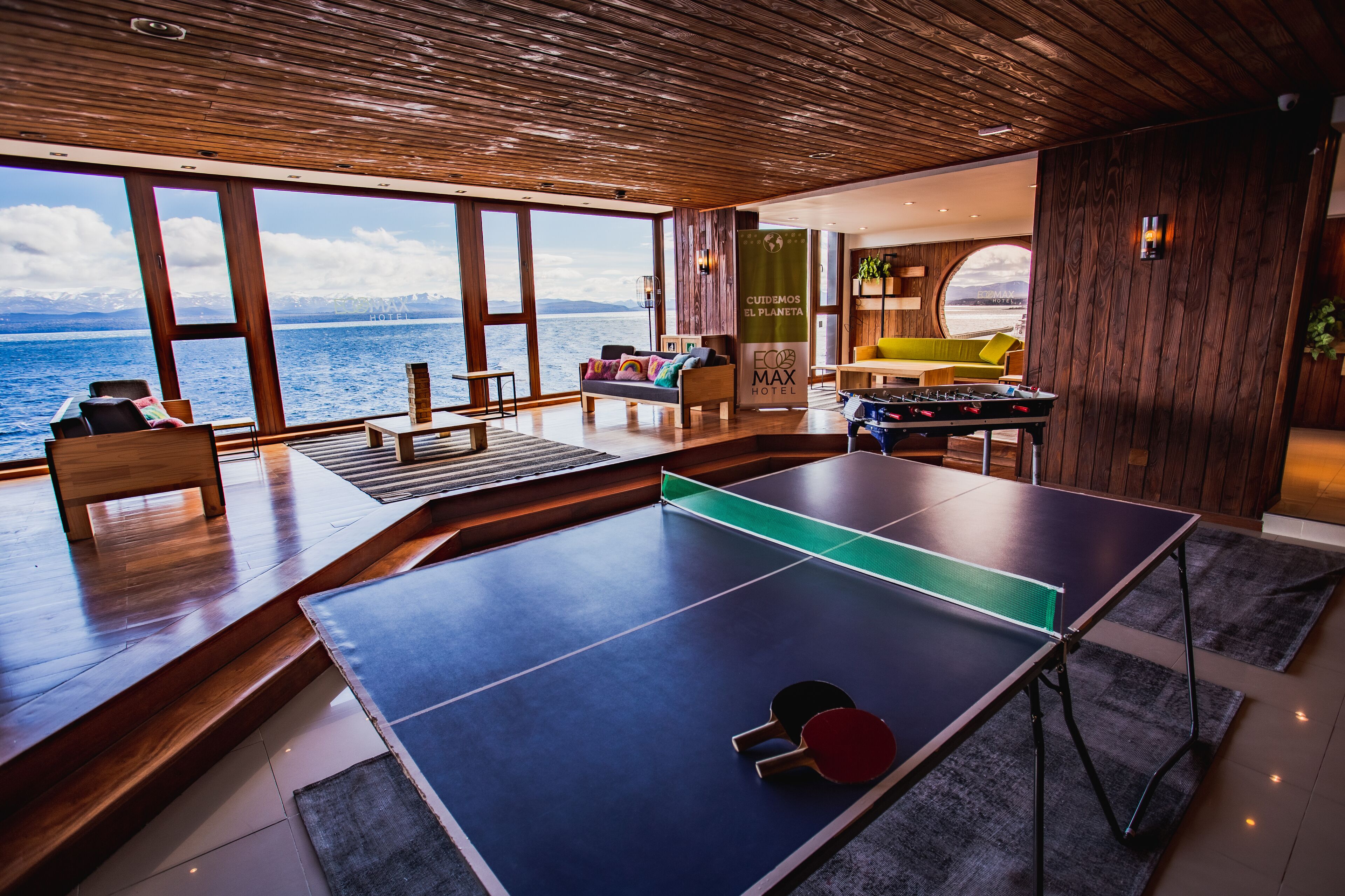 A modern hotel room with a ping pong table, a sofa, and a view of the sea.