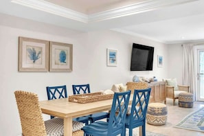 Zona pranzo con tavolo in legno, sedie blu e sedie in rattan.
