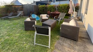 Un giardino sul retro con mobili da esterno, un tavolo e una zona riparata.