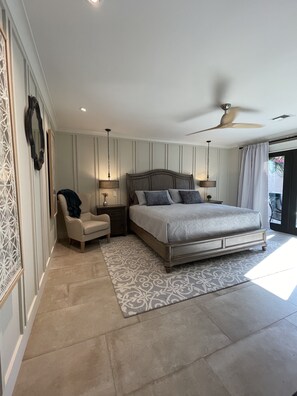 A bedroom with a large bed, a chair, a nightstand, a ceiling fan, and a patterned rug. - Luxurious Property with Dual Master Suites in McCormick Ranch (Scottsdale)