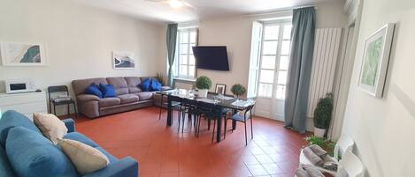 A living room with a sofa, a dining table, and a TV.
