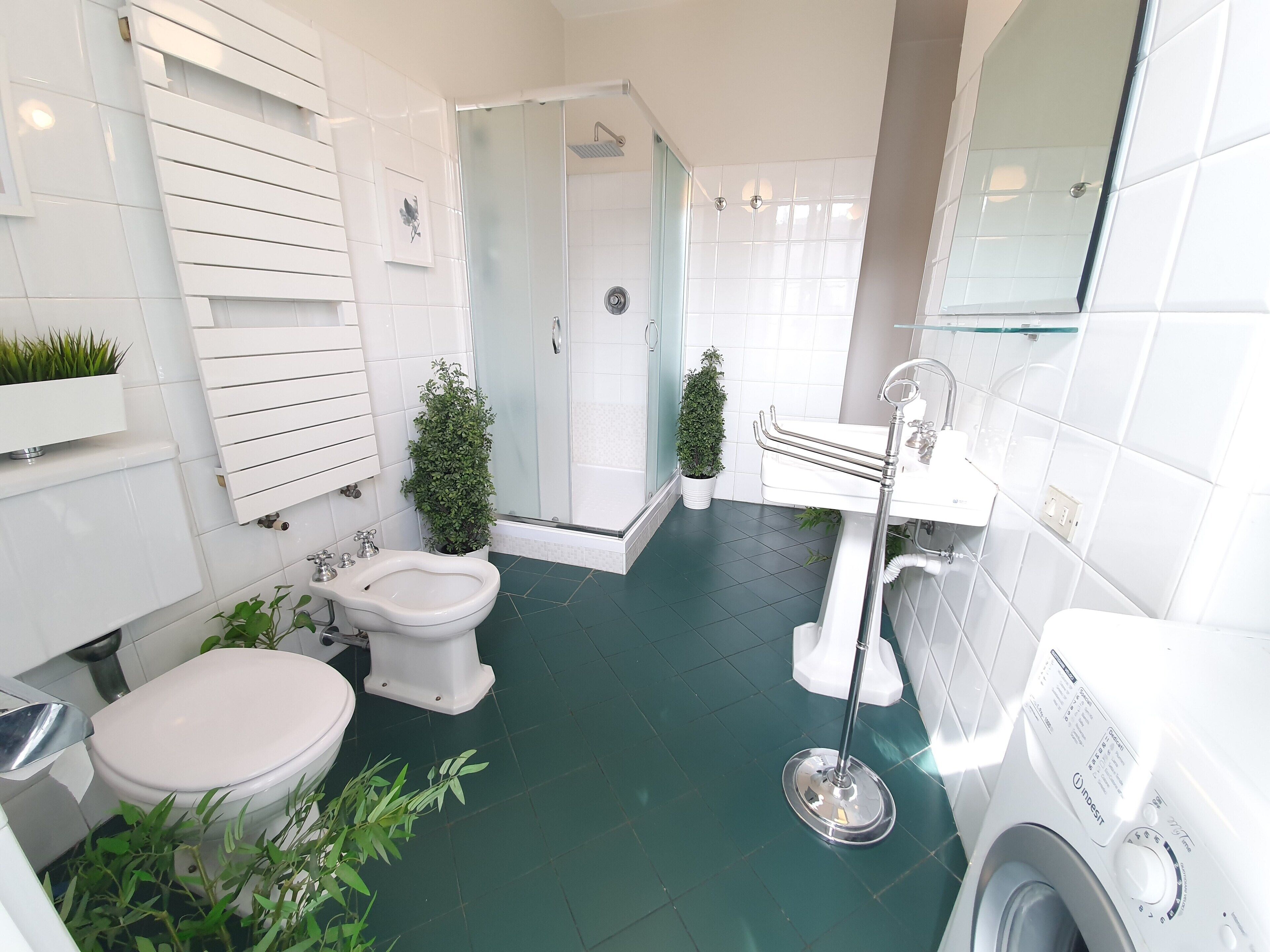 Casa de banho compacta com sanita, bidé e zona de duche com divisória de vidro.