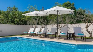 A swimming pool with lounge chairs and umbrellas. - Wonderful Villa Prisedi with Private Pool (Rakalj)