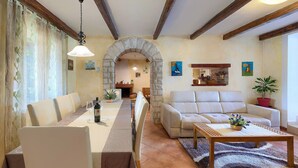 A dining area with a long table, chairs, and a chandelier. There is a stone archway leading to another room. - Wonderful Villa Prisedi with Private Pool (Rakalj)
