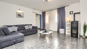 Una sala moderna con un sofá seccional gris, una mesa de centro blanca y un estufa de leña negra.