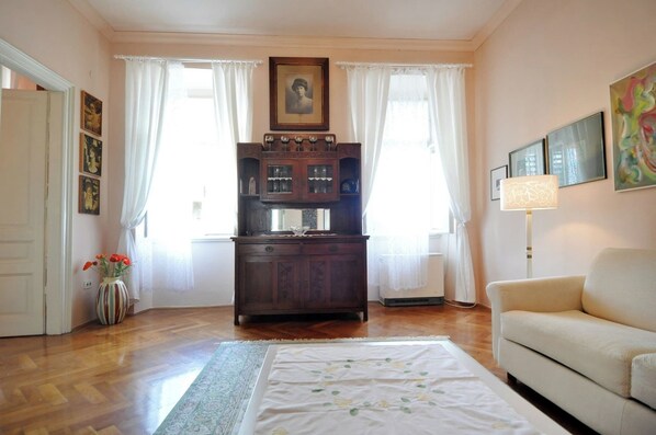 Una sala de estar con un sofá, un aparador de madera y un florero con flores.