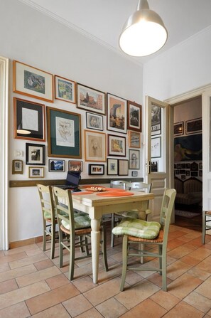 A dining area with a wooden table and chairs, surrounded by framed artwork on the walls.