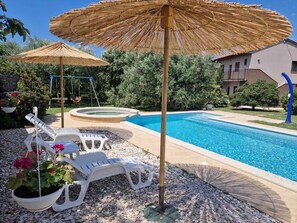 A swimming pool with lounge chairs and a swing set, surrounded by greenery and a building in the background. - Sabi Relax Zone Apartment - Private Pool, Jacuzzi (Pula)