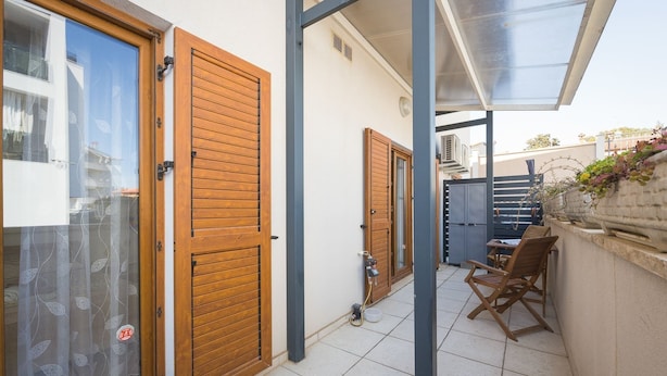 A covered outdoor area with wooden doors, a table with chairs, and a water dispenser. - Cute City Apt with a Relaxing Terrace - Tania (Pula)