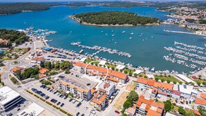 An aerial view of a coastal town with a marina, buildings with red roofs, and a clear blue sea. - Lovely Sea View Apartment - Belvi C1 (Medulin)