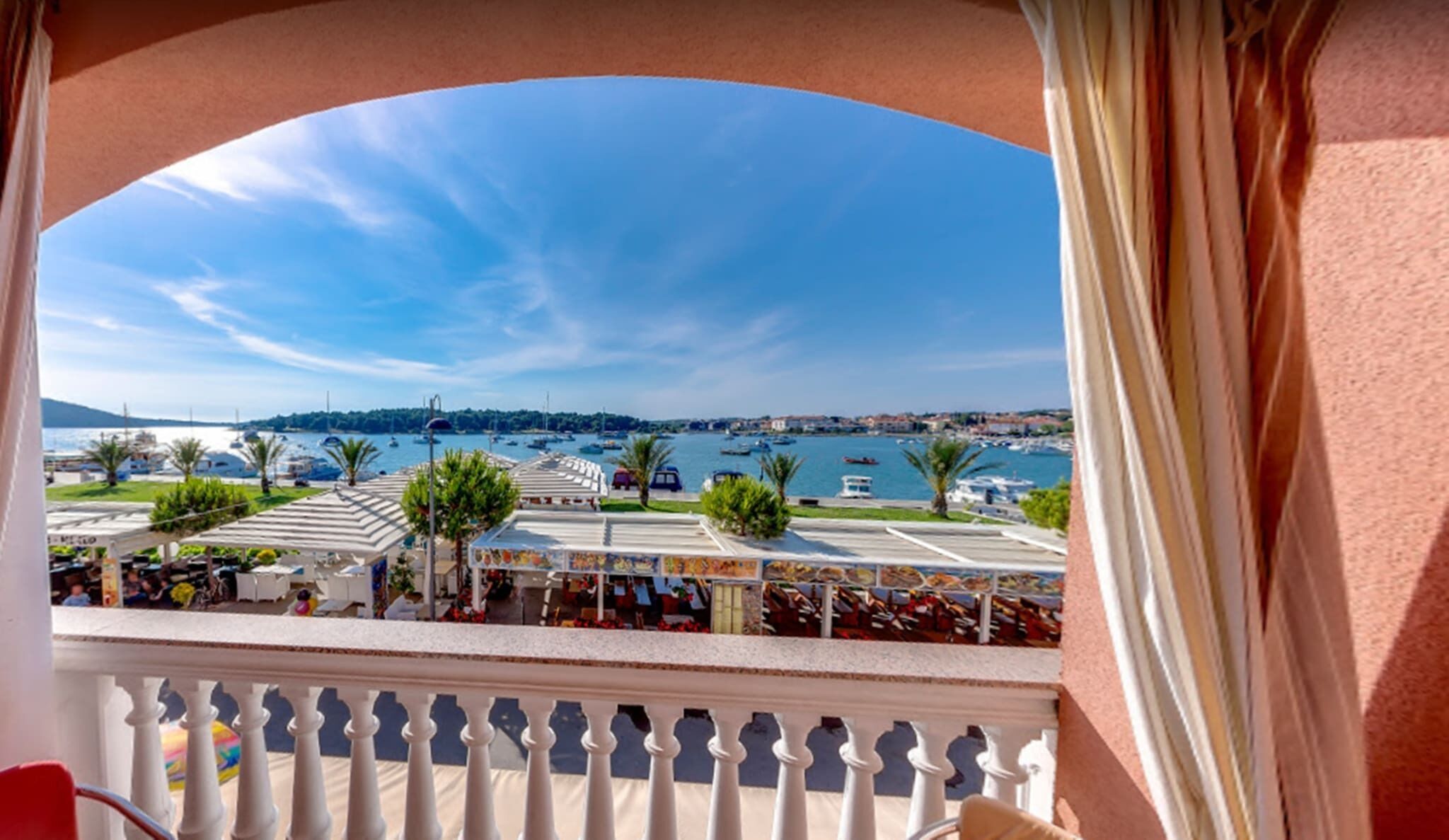 A balcony with a view of a marina, boats, and a distant cityscape.