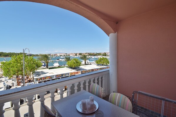 A balcony with a table, chairs, and a view of a marina with boats and buildings.