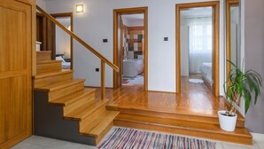 Un escalier en bois mène à une pièce où se trouvent un grand miroir, une plante en pot et une vue sur une salle de bain.