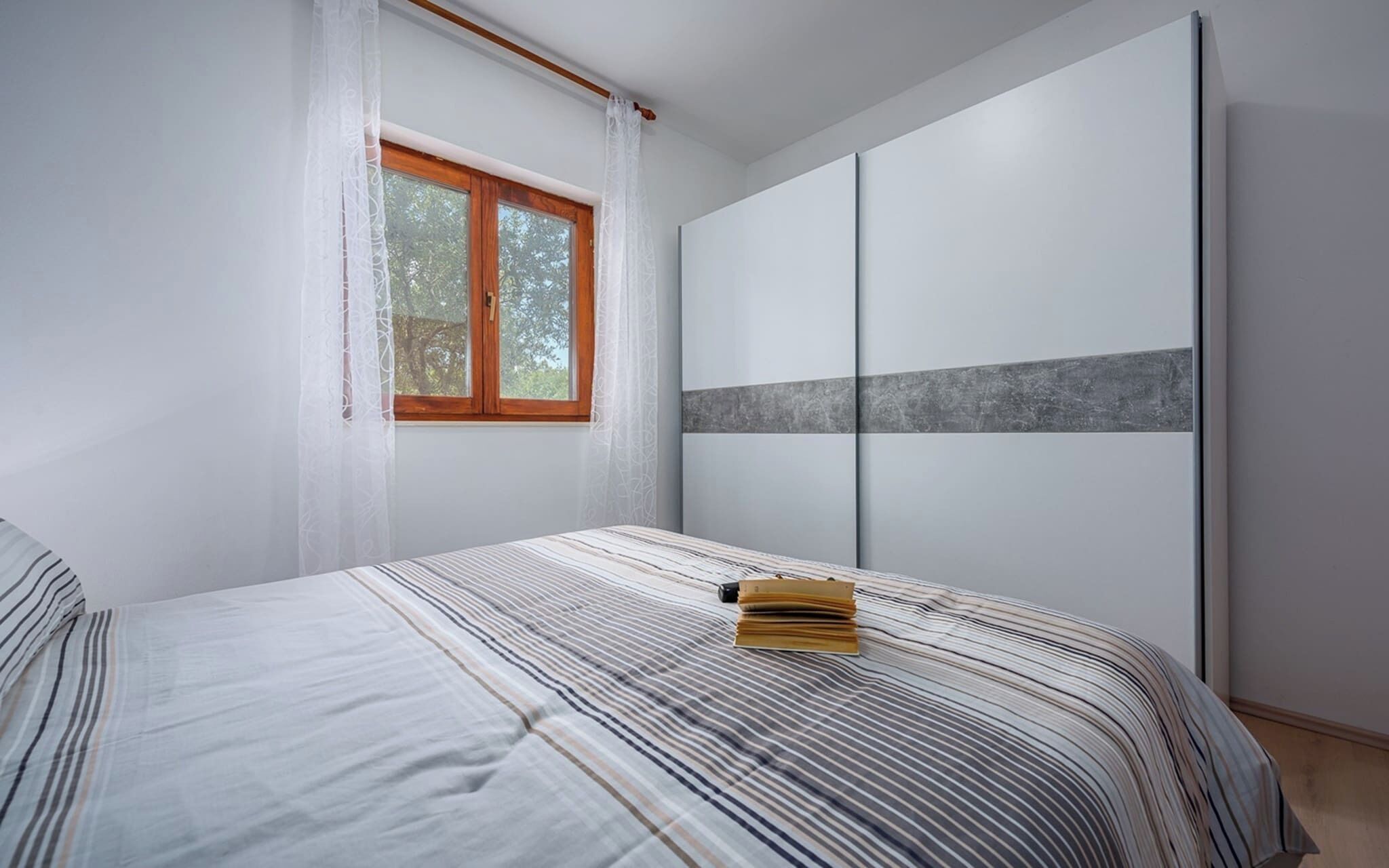 A bedroom with a bed, a window, and a wardrobe.