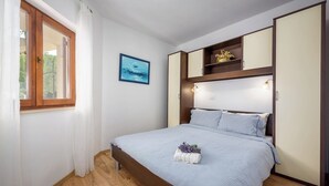 A bedroom with a bed, a window, a painting, and a shelf with decorative items. - Relaxing Summer Apartment - Pool, Sauna, Jacuzzi 6 (Drenje)