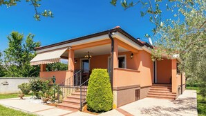 Een tweelaags huis met een overdekte veranda, een trap en een kleine tuin.