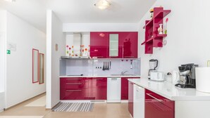 A modern kitchen with red and white cabinetry, a built-in dishwasher, and a coffee maker. - Villa Gigetto with Private Pool and Big Garden (Medulin)