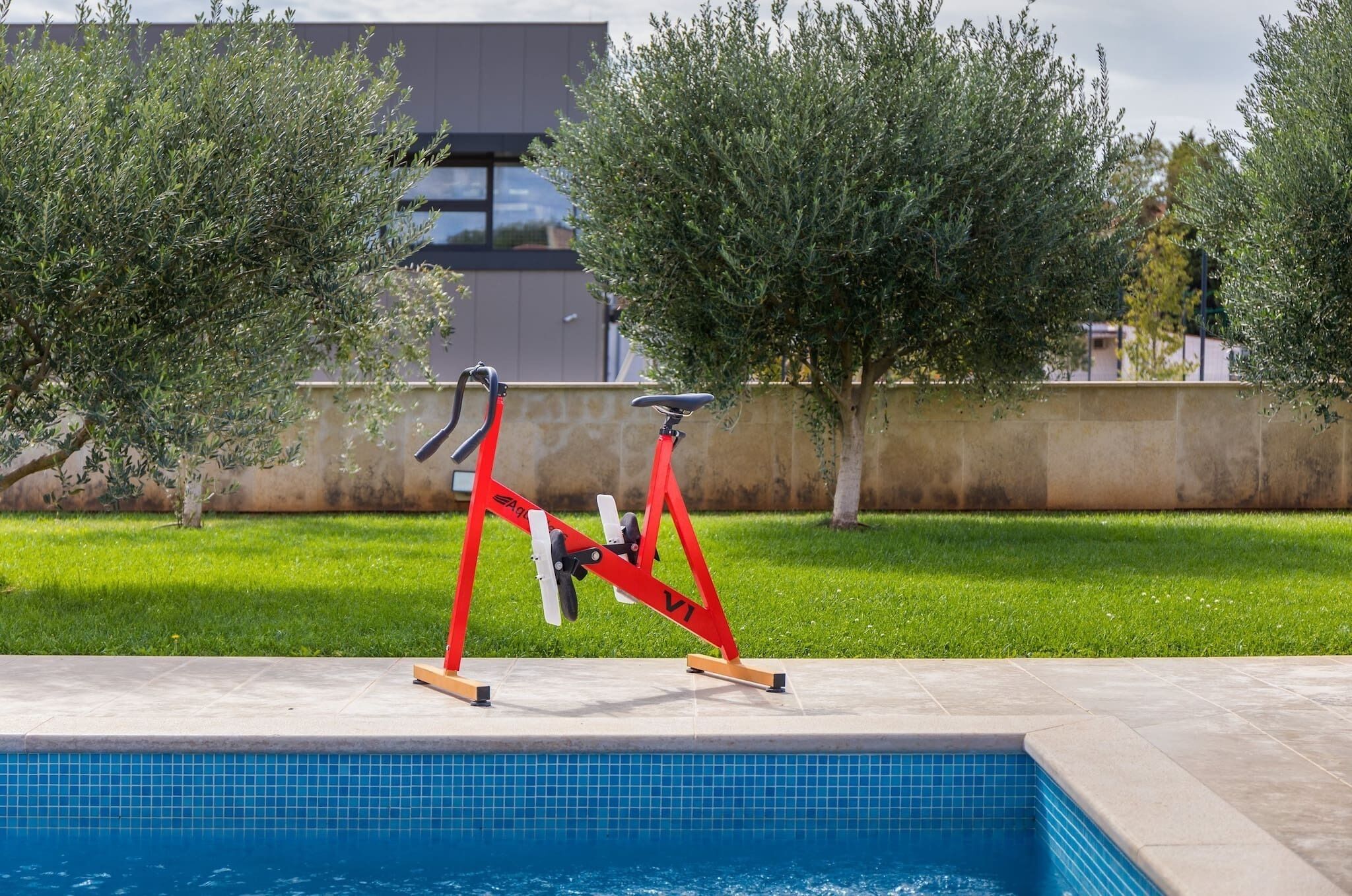 Une piscine avec un ensemble d’appareils de musculation rouges installé au bord.