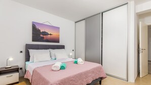 A bedroom with a bed, bedside tables, a nightstand, a painting, and a sliding door. - Villa Gigetto with Private Pool and Big Garden (Medulin)