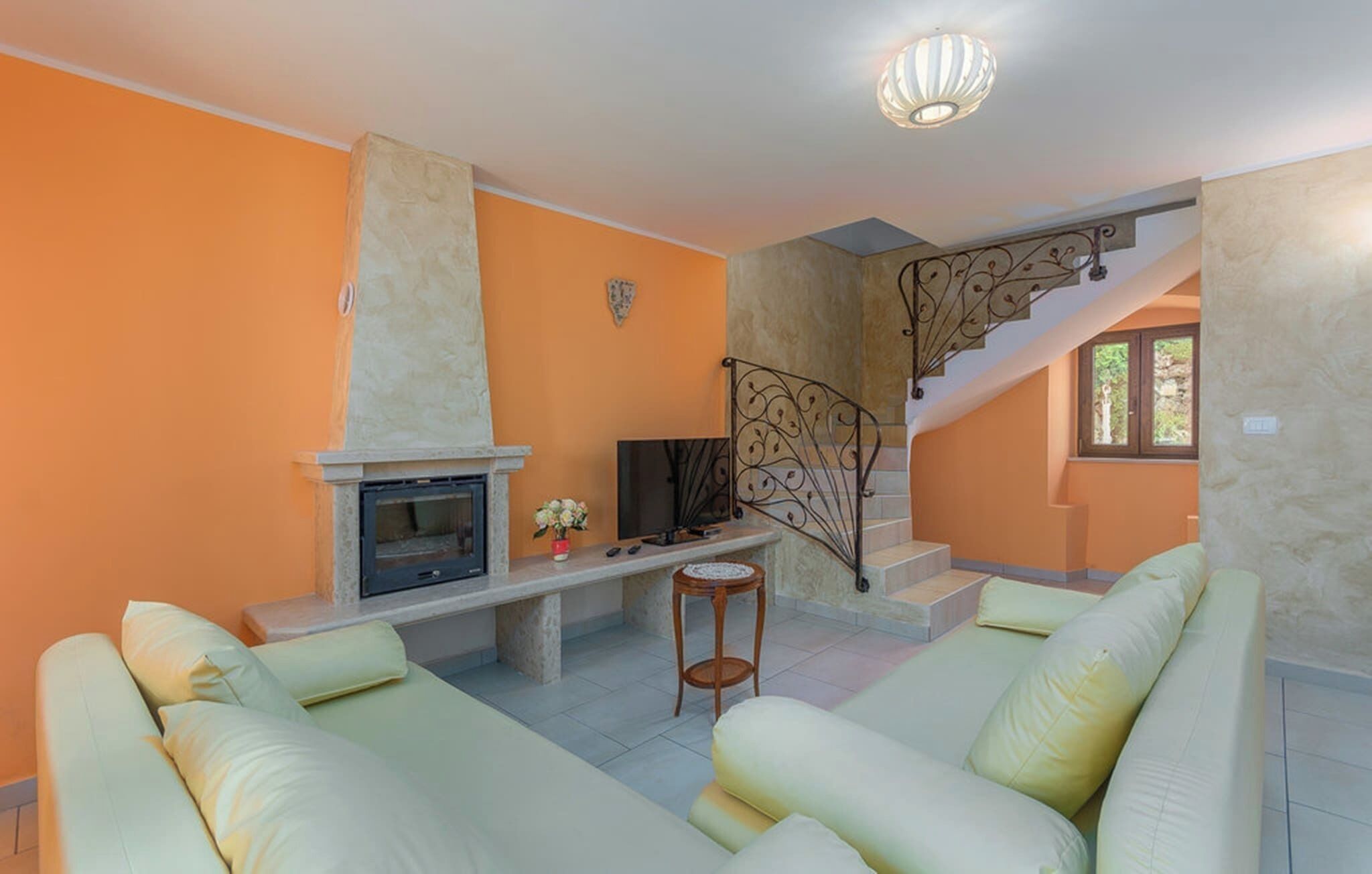 Un salon avec une cheminée, un canapé et un escalier.